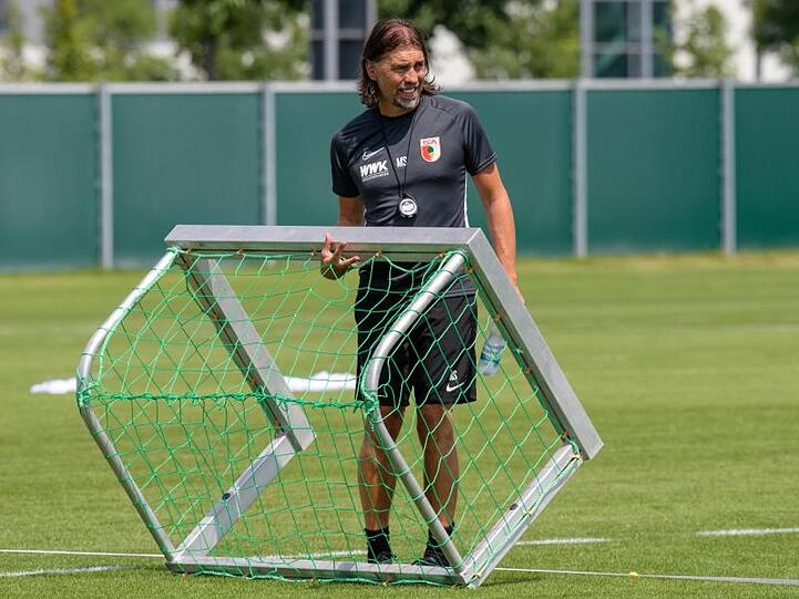 Martin Schmidt, Trainer des FC Augsburg, läuft mit einem Tor über den Trainingsplatz. Foto: Matthias Balk