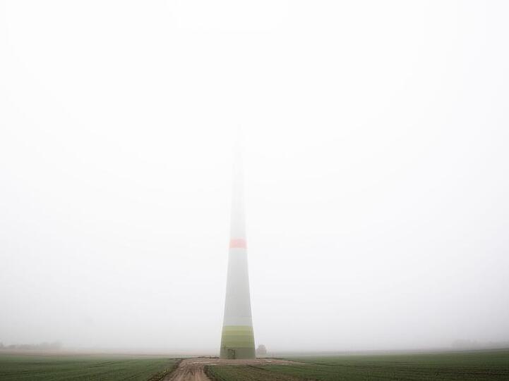 Ein Windrad verschwindet fast gänzlich in dichtem Nebel. Foto: Julian Stratenschulte/dpa/Archivbild
