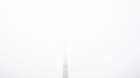 Ein Windrad verschwindet fast gänzlich in dichtem Nebel. Foto: Julian Stratenschulte/dpa/Archivbild