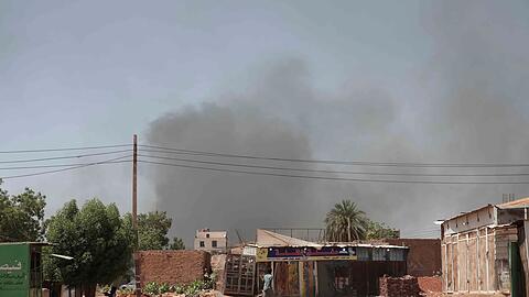 Rauch steigt hinter Gebäuden auf. Viele Menschen sind auf der Flucht vor dem Konflikt im Sudan.