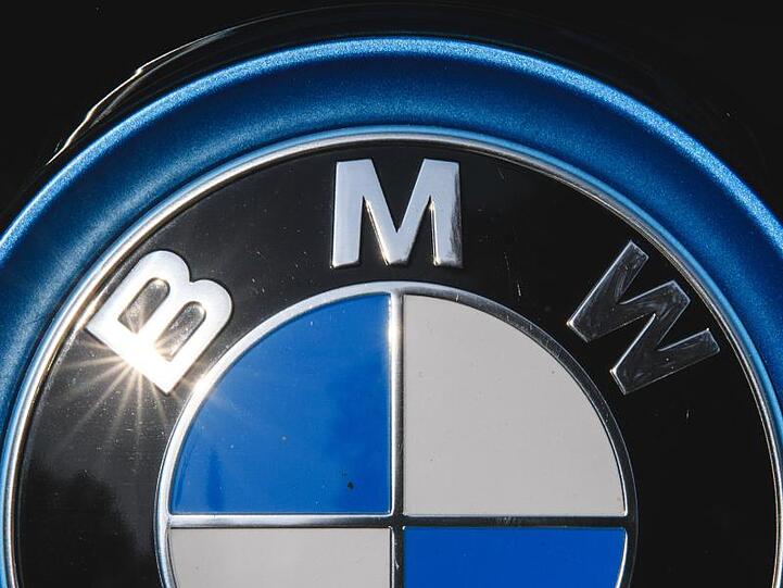 Die Sonne spiegelt sich in einem Logo des Autoherstellers BMW. (Archivbild)