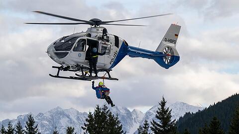 Ein Hundeführer der Bergrettung hängt mit Hilfe eines Seils an einem Hubschrauber.