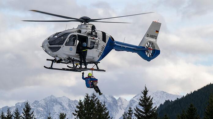 Ein Hundeführer der Bergrettung hängt mit Hilfe eines Seils an einem Hubschrauber.