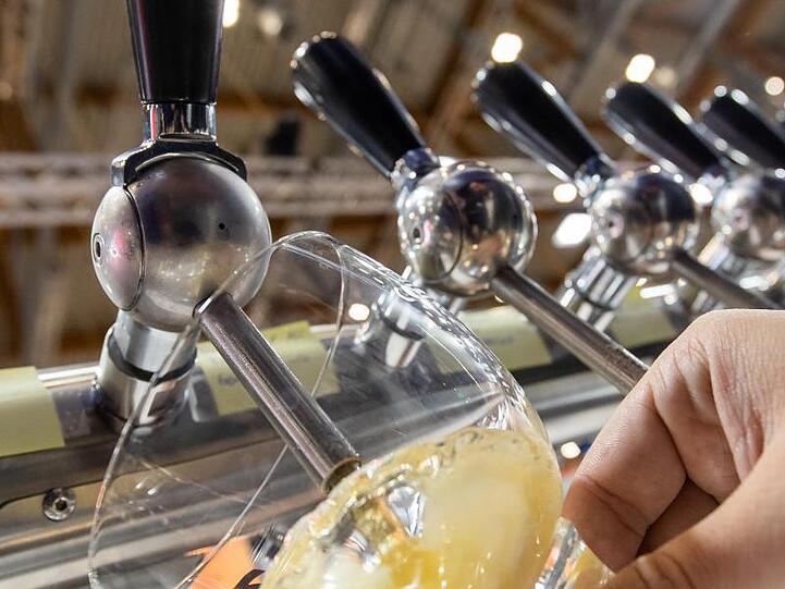 Ein Mitarbeiter eines Stands auf der Getränkemesse BrauBeviale zapft ein Bier. Foto: Daniel Karmann