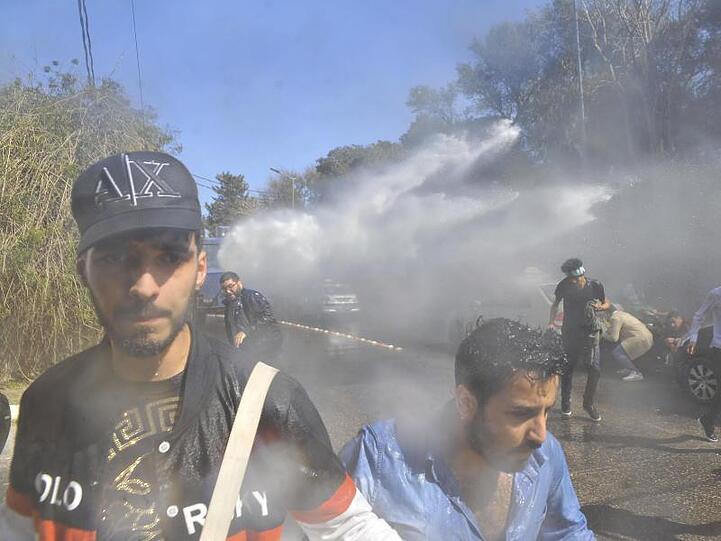 Demonstranten gehen in Algier vor einem Wasserwerfer der Polizei in Deckung.