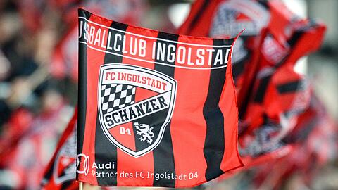 Fans von Ingolstadt winken mit Fahnen im Stadion.
