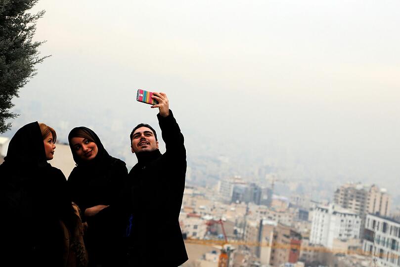 Auch in Iran kämpft man mittlerweile mit der Luftverschmutzung. Hier macht eine Gruppe junger Leute ein Selfie vor Smog-Kulisse.