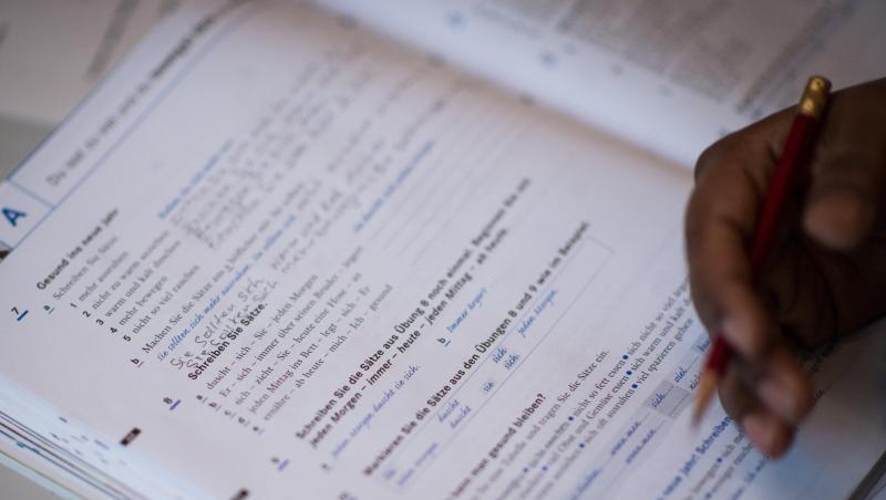 Eine Frau schreibt in ein Lehrbuch eines Integrationskurses. Foto: Sophia Kembowski/Archiv Eine Frau schreibt in ein Lehrbuch eines Integrationskurses. Foto: Sophia Kembowski/Archiv
