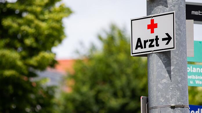Ein Schild mit der Aufschrift "Arzt" hängt an einer Straßenlaterne.