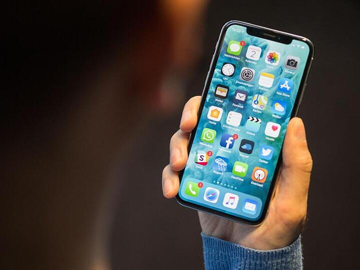 Ein Mann hält ein iPhone X in der Hand. Qualcomm hatte im Dezember ein Verkaufsverbot für die iPhone-Modelle 7, 8 und X in Deutschland erstritten.
