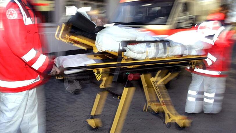 Ein Sanitäter bringt einen Patienten zum Rettungswagen. (Symbolbild)