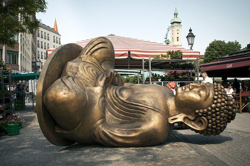 Den Münchner Viktualienmarkt ziert seit dem 8. Mai ein schräger Buddha-Skulptur "Made in Dresden", das Projekt des Malaysischen Künstlers Han Chong. Der unecht anmutende goldene Farbton der Skulptur und ihr einfaches Design erinnern an typische Souvenirartikel &ndash; ein kritischer Verweis auf die industrielle Massenproduktion als Phänomen unserer Zeit sowie auf die weitgehend unbekannte Tatsache, dass Billigartikel für den asiatischen Raum in Europa hergestellt werden.