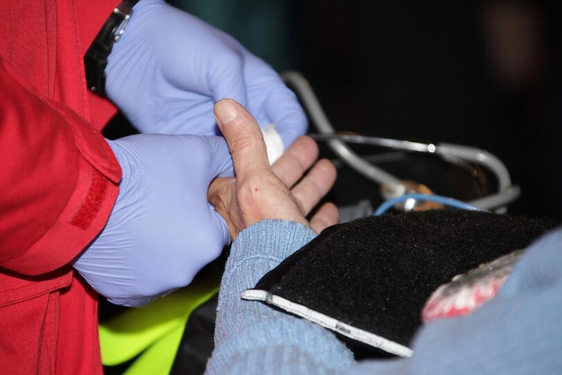 Vorsichtig behandelt der Sanitäter einen älteren Patienten.