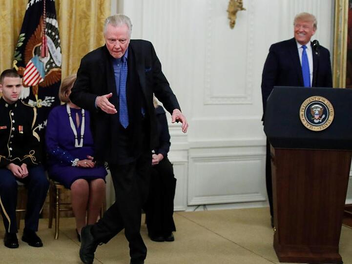 Jon Voight tanzt und Donald Trump lächelt.