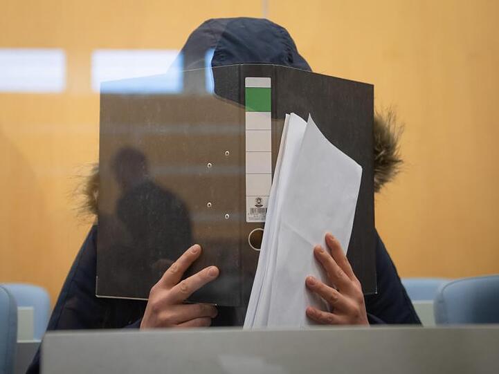 Die Angeklagte verbirgt im Düsseldorfer Oberlandesgericht ihr Gesicht hinter einem Aktenordner.