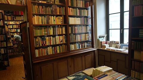 In der Vitrine, an den Wänden, über dem Durchgang: Egal, wohin man im Antiquariat Hofmann blickt, man ist umgeben von Büchern. Die dunklen Holzregale hat Hofmanns mittlerweile verstorbener Ehemann einst selbst für den Laden gebaut.