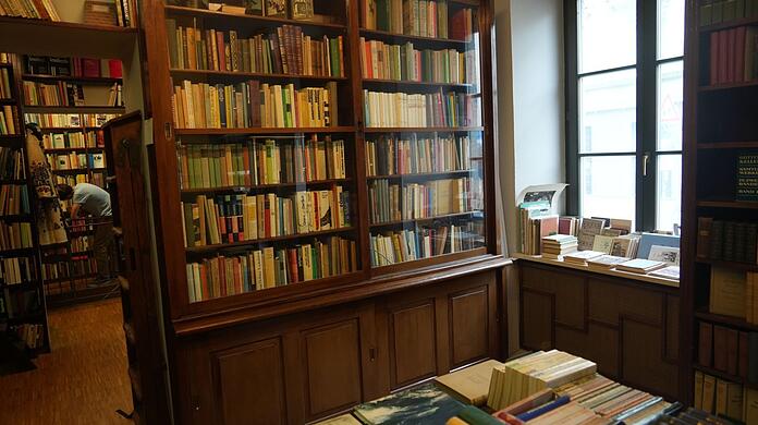 In der Vitrine, an den Wänden, über dem Durchgang: Egal, wohin man im Antiquariat Hofmann blickt, man ist umgeben von Büchern. Die dunklen Holzregale hat Hofmanns mittlerweile verstorbener Ehemann einst selbst für den Laden gebaut.
