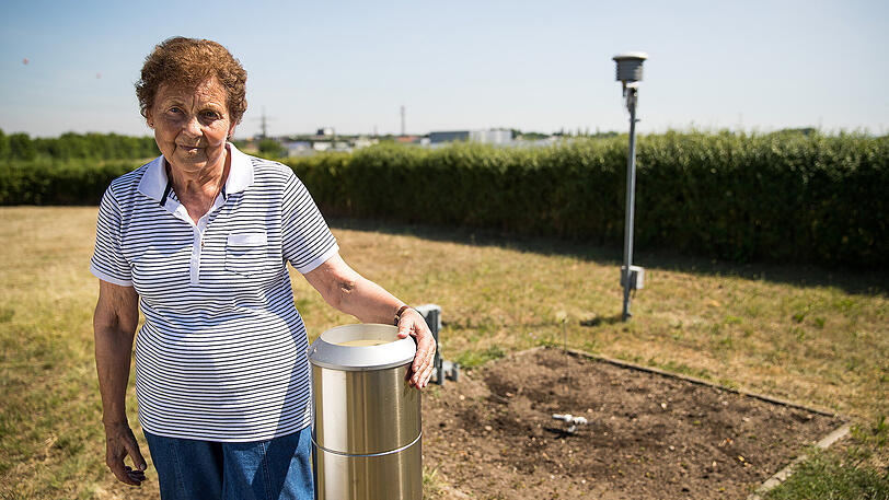Magdalena Michelsen steht auf ihrem Grundstück in Kitzingen neben einer Messstation des Deutschen Wetterdienstes (DWD).