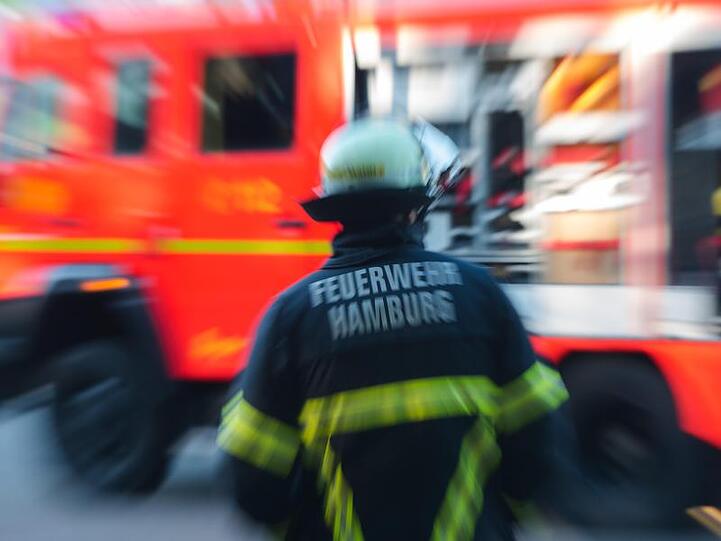 Ein Feuerwehrmann steht in Hamburg vor einem Löschfahrzeug. Foto: Daniel Bockwoldt/Archivbild