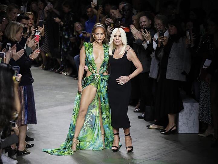 Die Schauspielerin und Tänzerin Jennifer Lopez (l) und die italienische Designerin Donatella Versace nehmen nach der Modenschau den Applaus des Publikums entgegen.