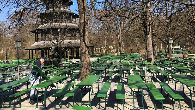 Der Biergarten am Chinesischen Turm ist vorerst geschlossen. Ein Arbeiter macht sich schon einmal an den grünen Bierbänken zu schaffen, die braucht es jetzt ja nicht mehr.