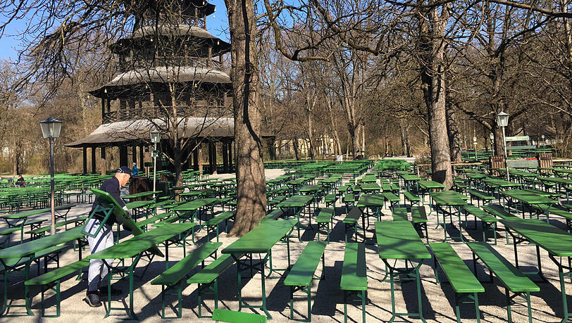 Der Biergarten am Chinesischen Turm ist vorerst geschlossen. Ein Arbeiter macht sich schon einmal an den grünen Bierbänken zu schaffen, die braucht es jetzt ja nicht mehr.