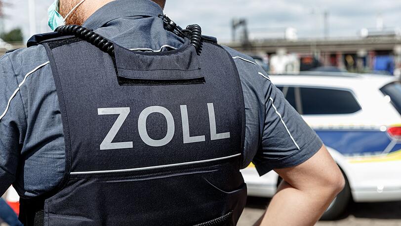 Ein Beamter trägt während seines Dienstes eine Schutzweste mit der Rückenaufschrift "Zoll".