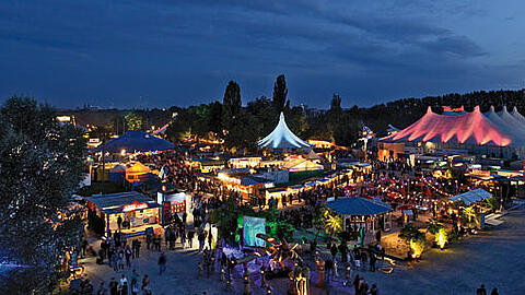 Bald gibt's das wieder am Olympiapark: Das hell erleuchtete Tollwood-Gelände in der Nacht.