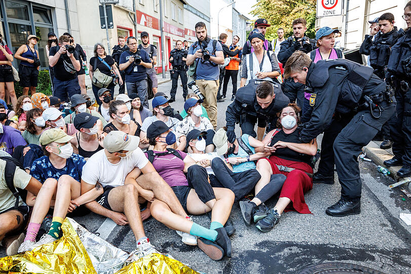 Polizisten lösen eine Straßenblockade vom Bündnis "No Future for IAA" im Rahmen der IAA MOBILITY 2023 auf und tragen die Aktivisten zu den Polizei-Einsatzfahrzeugen.