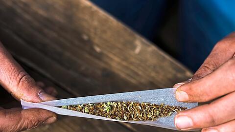 Vor einem Jahr hat es die Ampel legalisiert: Eine Person dreht Tabak und Cannabis in ein Zigarettenpapier. 365 Tage nach Inkrafttreten der neuen Regelungen zu Cannabis lässt sich eine erste Bilanz ziehen.