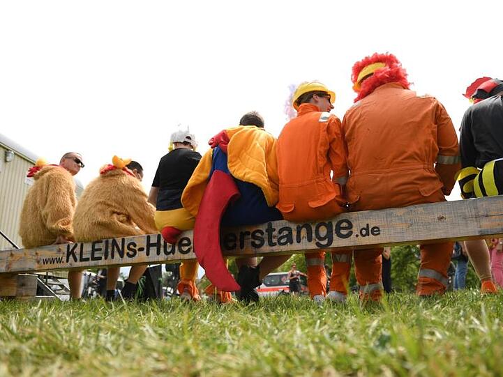 Teilnehmer der 6. Deutschen Gockelkrähmeisterschaft auf einer Hühnerstange. Foto: Arne Dedert
