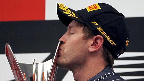 Red-Bull-Pilot Sebastian Vettel küsst bei der Siegerehrung in Indien seinen Pokal.