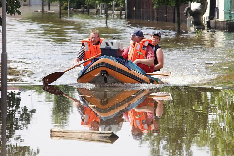 2013: Verheerendes Hochwasser in Fischerdorf - Helfer fahren die Anwohner im Boot zu ihren Häusern zur Schadensbegutachtung.