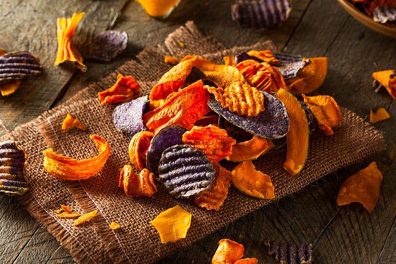 Sind die Gem&uuml;sescheiben zu dick, bleiben die Chips weich. Geben Sie die Scheiben in eine Sch&uuml;ssel und mischen Sie einen Essl&ouml;ffel Oliven&ouml;l sowie Kr&auml;uter oder Gew&uuml;rze wie Paprika, Chili, Zimt oder Pfeffer dazu. Verteilen Sie die Chips einzeln auf einem Backblech, ohne dass sie sich &uuml;berlappen. Backen Sie sie etwa 40 bis 50 Minuten lang, bis sie leicht gebr&auml;unt sind. &Ouml;ffnen Sie den Ofen zwischendurch, damit die Feuchtigkeit entweicht und die Chips knusprig werden.