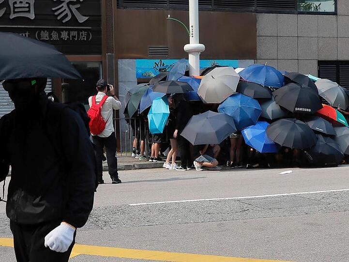 Die Schirme von Hongkong: Regierungskritische Demonstranten schützen sich damit nicht nur vor Tränengas, sondern auch vor Überwachungskameras. Hier versuchen sie, eine Kamera zu demontieren.