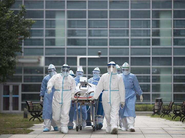Medizinisches Personal mit einem Covid-19-Patienten im chinesischen Wuhan. Einer Studie zufolge entwickelten sich die Corona-Hotspots in Regionen mit ähnlichen Klimafaktoren.