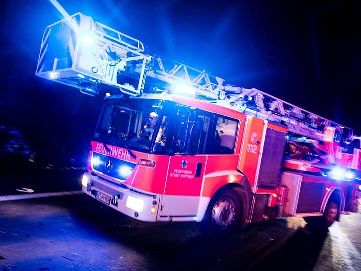 Ein Drehleiterwagen der Feuerwehr fährt mit Blaulicht an einer Unfallstelle vorbei. Foto: Marcel Kusch/dpa/Illustration