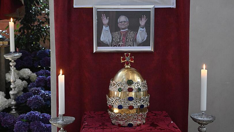 In der Münchner Stadtpfarrkirche ist die Tiara der Petrusfigur vor einem Bild des neuen Papstes Leo XIV. zu sehen. In der Münchner Stadtpfarrkirche ist die Tiara der Petrusfigur vor einem Bild des neuen Papstes Leo XIV. zu sehen.