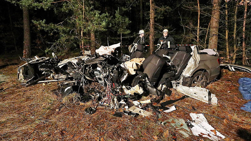Feuerwehrleute stehen neben dem Autowrack, in dem der 37-Jährige ums Leben gekommen ist.