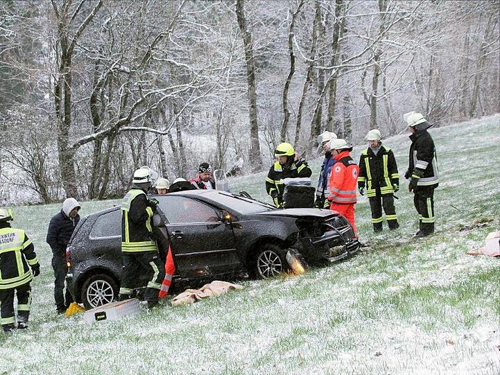 Rettungskräfte stehen neben einem auf Schneeglätte verunglückten Fahrzeug bei Frasdorf im Landkreis Rosenheim. Foto: Josef Reisner