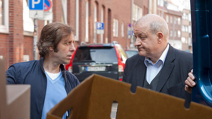 "Wilsberg: Mundtot": Ekki (Oliver Korittke, l.) will die Kartons nicht ausladen. Wilsbergs (Leonard Lansink) Bücher wurden gepfändet