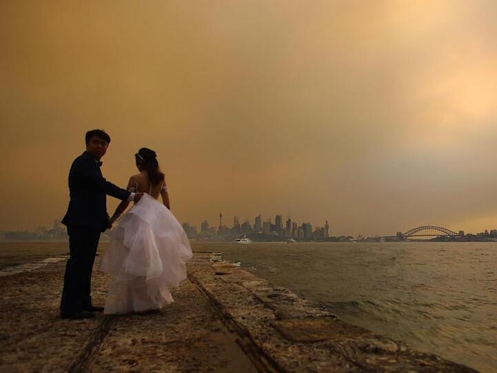 Traumkulisse zum "schönsten Tag im Leben"? Keine Chance! Ein Brautpaar lässt sich vor der von Rauchschwaden verhangenen Skyline von Sydney fotografieren.