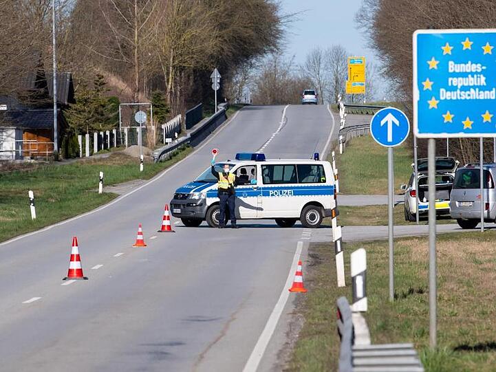 Polizisten stehen an der Bundesstraße 512 an einer Kontrollstelle an der Grenze zu Österreich. Foto: Sven Hoppe/dpa/Archivbild