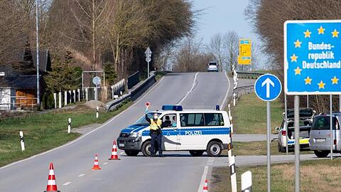 Polizisten stehen an der Bundesstraße 512 an einer Kontrollstelle an der Grenze zu Österreich. Foto: Sven Hoppe/dpa/Archivbild