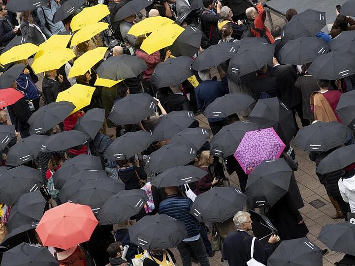 Mit Regenschirmen beteiligen sich zahlreiche Menschen auf der Buchmesse an einer Mahnwache für die Meinungsfreiheit.
