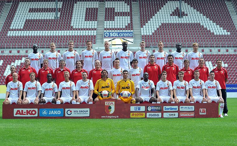 Die Mannschaft des Fußball-Bundesligisten FC Augsburg, posiert am 26.07.2012 beim offiziellen Fototermin des Vereins für die Saison 2012-13 in der SGL-Arena Augsburg (Schwaben) für das Mannschaftsfoto. (vorne l-r) Tobias Werner, Marcel de Jong, Knowledge Musona, Matthias Ostrzolek, Sascha Mölders, Torwart Simon Jentzsch, Torwart  Ioannis Gelios, Giovanni Sio, Paul Verhaegh, Marco Thiede, Daniel Baier, Milan Petrzela, (Mitte l-r) Zeugwart Salvatore Belardo, Physiotherapeut Markus Zeyer, Physiotherapeut James Morgan, Mannschaftsarzt Ulrich Boenisch, Mannschaftsarzt Andreas Weigel; Mannschaftsarzt Peter Stiller, Ronny Philip, Jan Moravek, Athletiktrainer Thomas Barth, Torwarttrainer Zdenko Miletic, Co-Trainer Wolfgang Beller, Assistenztrainer Tobias Zellner, Trainer Markus Weinzierl, (hinten l-r) Dawda Bah, Ragnar Klavan, Sebastian Langkamp, Torsten Oehrl, Kevin Vogt, Aristide Bance, Jan-Ingwer Callsen-Bracker, Dominik Reinhardt, Gibril Sankoh, Andreas Ottl.