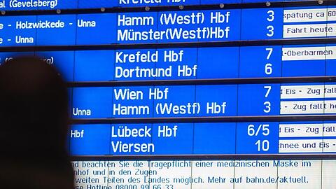Ein Mann steht am Hauptbahnhof Hagen vor der Anzeigetafel, auf der zahlreiche Züge als ausgefallen und verspätet angekündigt sind.