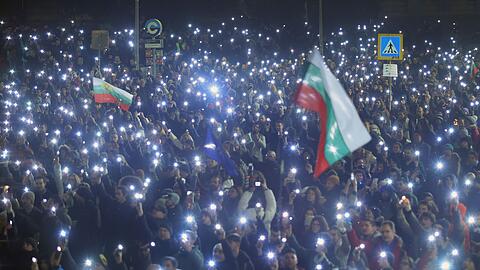 Menschen gingen mit Flaggen und Lichtern auf die Stra&szlig;e.