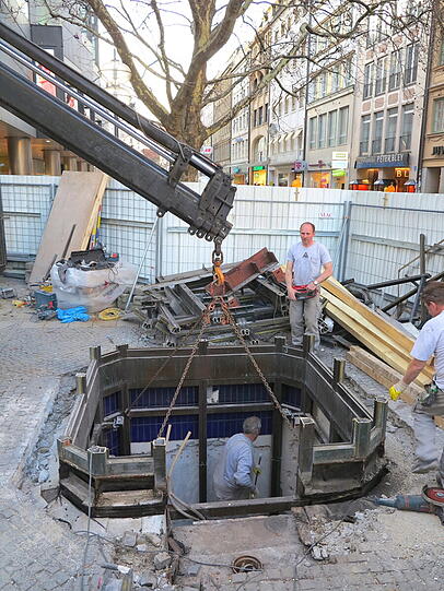 Mit dem Kran heben die Bauarbeiter den alten Aufzug zwischen Sperrengeschoss und Oberfläche am Marienplatz aus den Fugen.