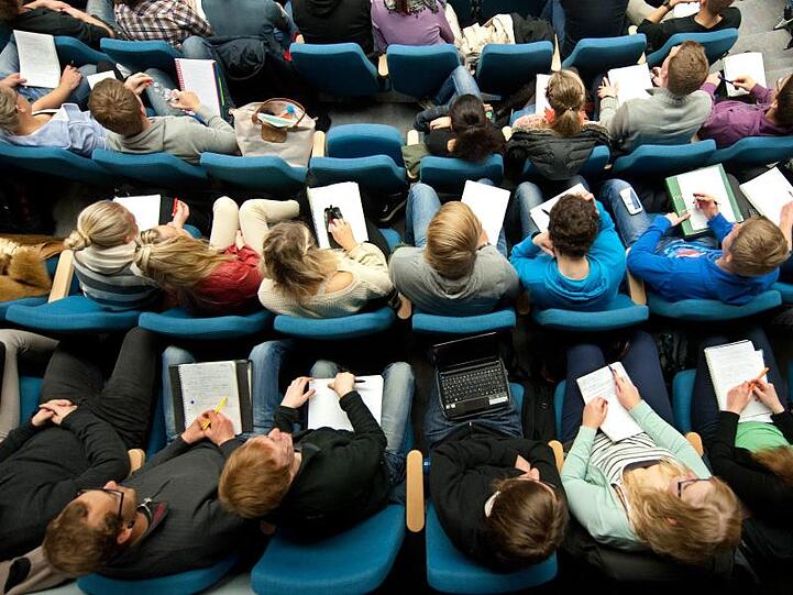 Studenten sitzen in einer Vorlesung in einem Hörsaal. Foto: Julian Stratenschulte/dpa